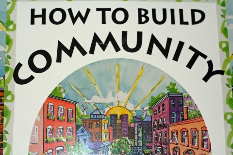 Plakat mit Aufschrift 'How to build community' und bunten Häusern