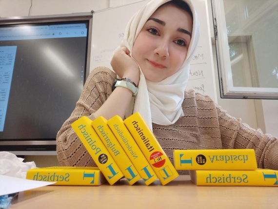 Yomna Moawed sitzt an einem Tisch mit vielen Wörterbüchern vor sich.