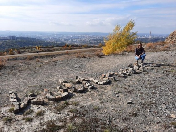Amelie hockt neben einem Schriftzug aus Steinen auf einem Berg.